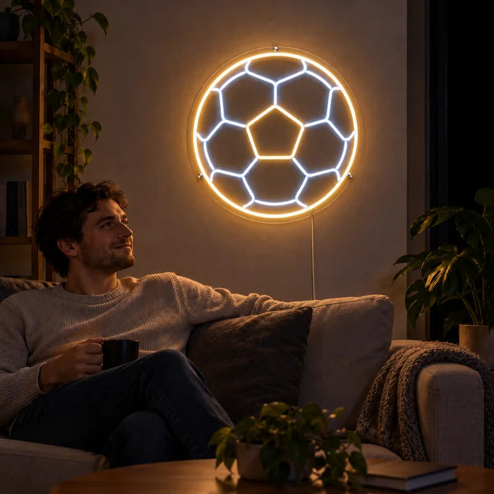 Fußball Neon LED Schild an der Wohnzimmerwand, davor entspannt eine Person auf dem Sofa