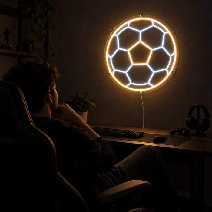 Fußball Neon LED Schild über dem Gaming-Schreibtisch, davor ein Spieler im Gaming-Stuhl