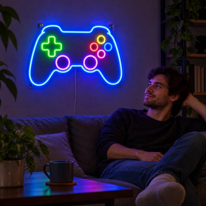 Gamecontroller Neon LED Schild an der Wohnzimmerwand, davor entspannt eine Person auf dem Sofa