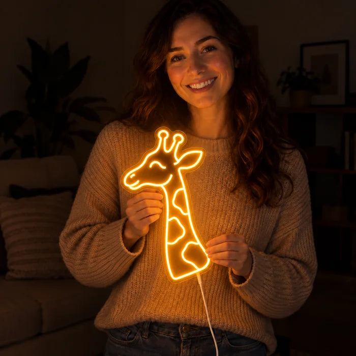 Giraffenkopf Neon LED Schild in den Händen einer lächelnden Frau vor dunklem Hintergrund