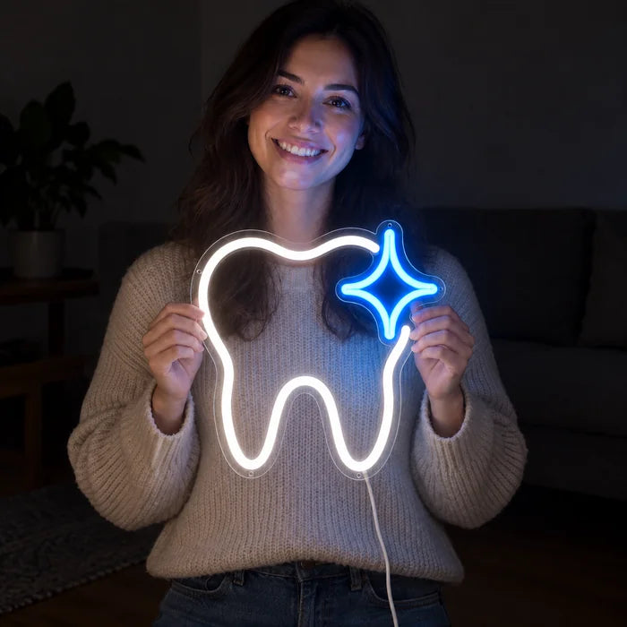 Glänzender Zahn Neon LED Schild in den Händen einer lächelnden Frau vor dunklem Hintergrund