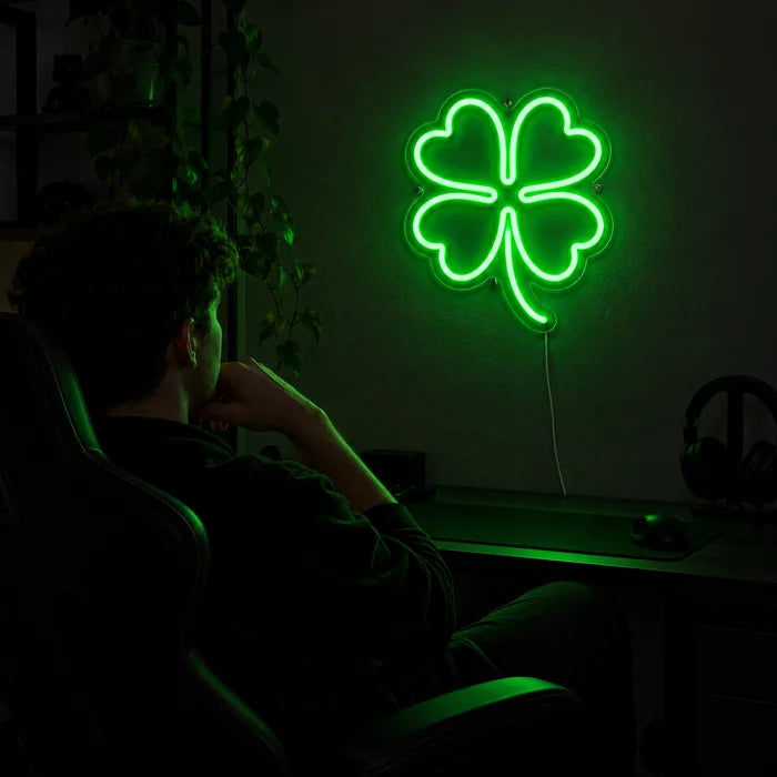 Glücksklee Neon LED Schild über dem Gaming-Schreibtisch, davor ein Spieler im Gaming-Stuhl