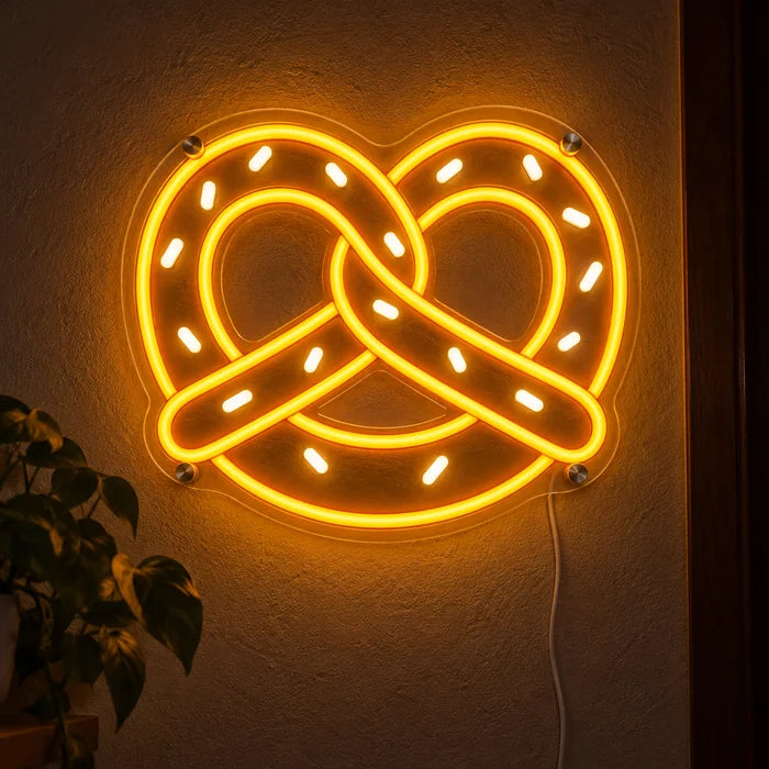 Goldene Brezel Neon LED Schild leuchtend an einer dunklen Wand, Nahaufnahme mit Anschlusskabel