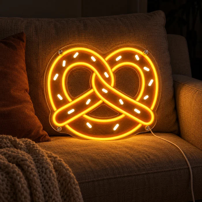 Goldene Brezel Neon LED Schild auf einem gemütlichen Sofa zwischen Kissen und Decke