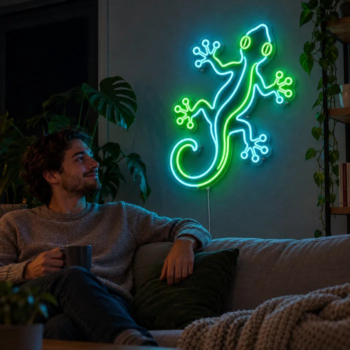 Grüner Gecko Neon LED Schild an der Wohnzimmerwand, davor entspannt eine Person auf dem Sofa