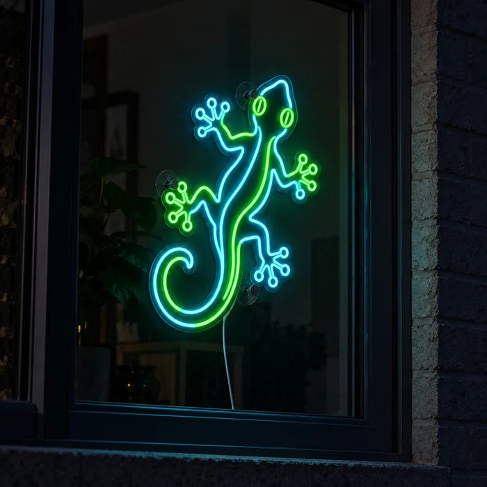 Grüner Gecko Neon LED Schild im Fenster, von der nächtlichen Straße aus gesehen