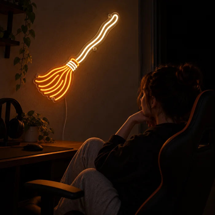 Hexenbesen Neon LED Schild über dem Gaming-Schreibtisch, davor ein Spieler im Gaming-Stuhl