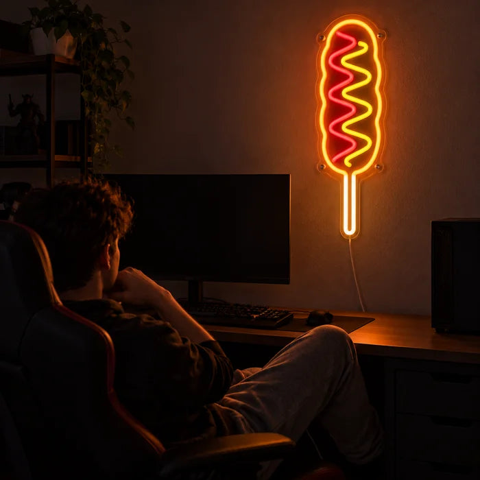 Hotdog am Stiel Neon LED Schild über dem Gaming-Schreibtisch, davor ein Spieler im Gaming-Stuhl