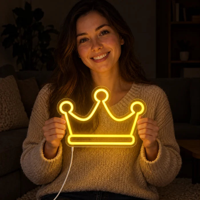 Königskrone Neon LED Schild in den Händen einer lächelnden Frau vor dunklem Hintergrund