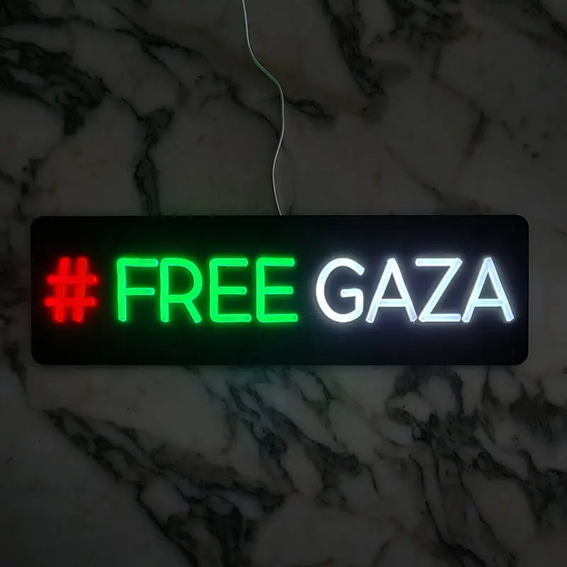 Neon-Schild mit dem Text "#FREE GAZA", wobei "FREE" in hellem Grün und "GAZA" in leuchtendem Weiß dargestellt ist.
