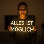 Modernes, individuelles Neon-Licht mit dem Text "ALLES IST MÖGLICH" als Wanddekoration auf dunklem Hintergrund.