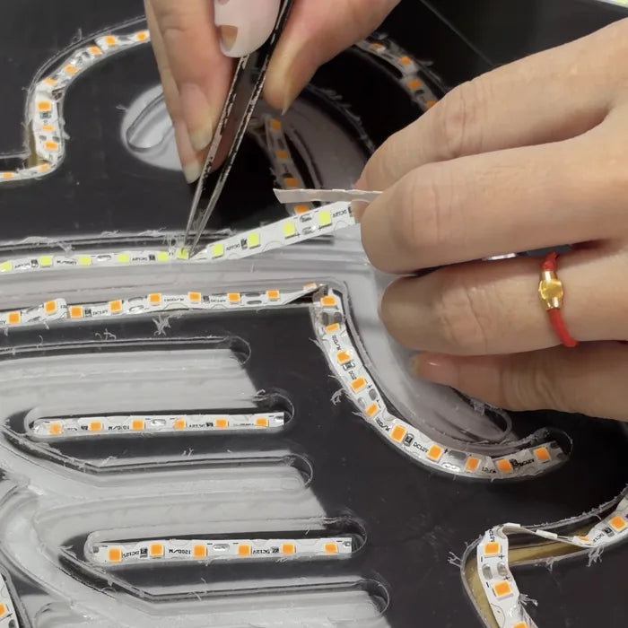 LED-Streifen werden von Hand in die Acrylkanäle gesetzt