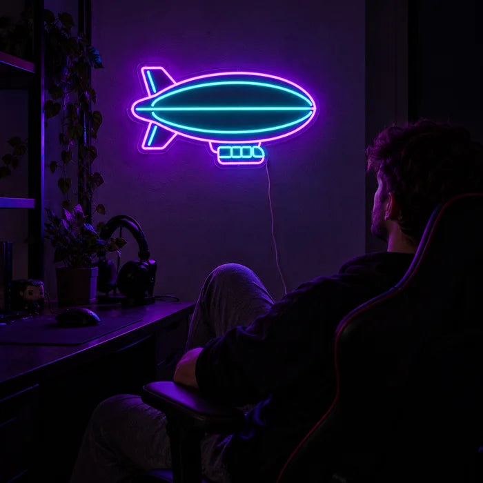 Luftschiff Neon LED Schild über dem Gaming-Schreibtisch, davor ein Spieler im Gaming-Stuhl