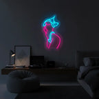 Moderne Kunst-Deko: Ein Neon-Motiv einer weiblichen Figur in Pink und Weiß vor einer grauen Betonwand.

