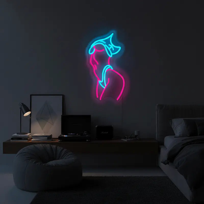 Moderne Kunst-Deko: Ein Neon-Motiv einer weiblichen Figur in Pink und Weiß vor einer grauen Betonwand.
