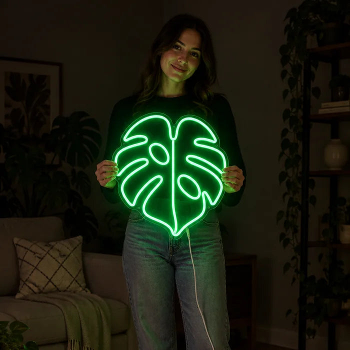 Monstera Neon LED Schild von einer Frau gehalten, zeigt die Größe im Vergleich zum Körper