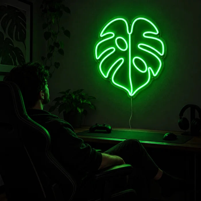 Monstera Neon LED Schild über dem Gaming-Schreibtisch, davor ein Spieler im Gaming-Stuhl