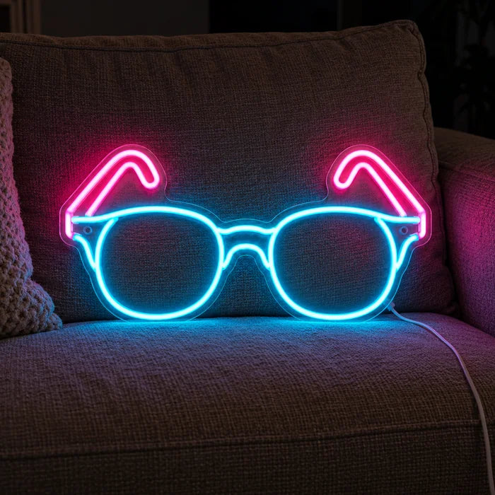 Neon-Brille Neon LED Schild auf einem gemütlichen Sofa zwischen Kissen und Decke