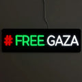 Leuchtschild mit der Aktivisten-Botschaft FREE GAZA, beleuchtet in markanten Farben vor einem dunklen Hintergrund.
