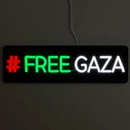 Leuchtschild mit der Aktivisten-Botschaft FREE GAZA, beleuchtet in markanten Farben vor einem dunklen Hintergrund.
