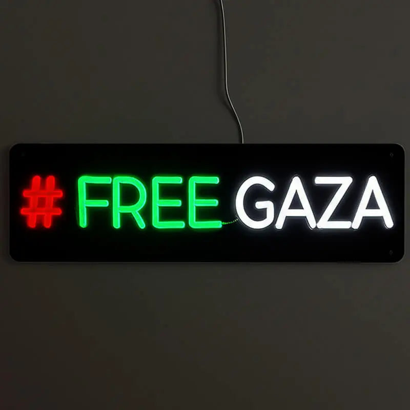Leuchtschild mit der Aktivisten-Botschaft FREE GAZA, beleuchtet in markanten Farben vor einem dunklen Hintergrund.
