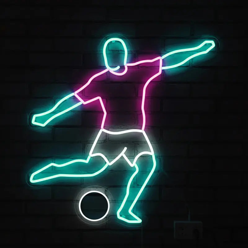 Neon-Schild in Form eines Fußballspielers beim Schuss; das Trikot ist pink, die Beine und Arme sind blau