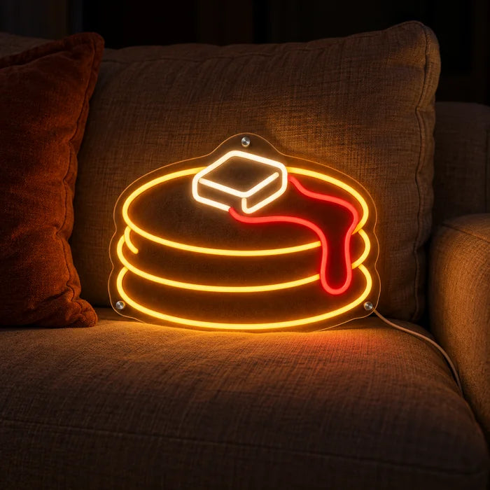 Pfannkuchen Neon LED Schild auf einem gemütlichen Sofa zwischen Kissen und Decke
