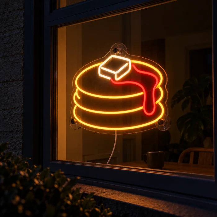 Pfannkuchen Neon LED Schild im Fenster, von der nächtlichen Straße aus gesehen