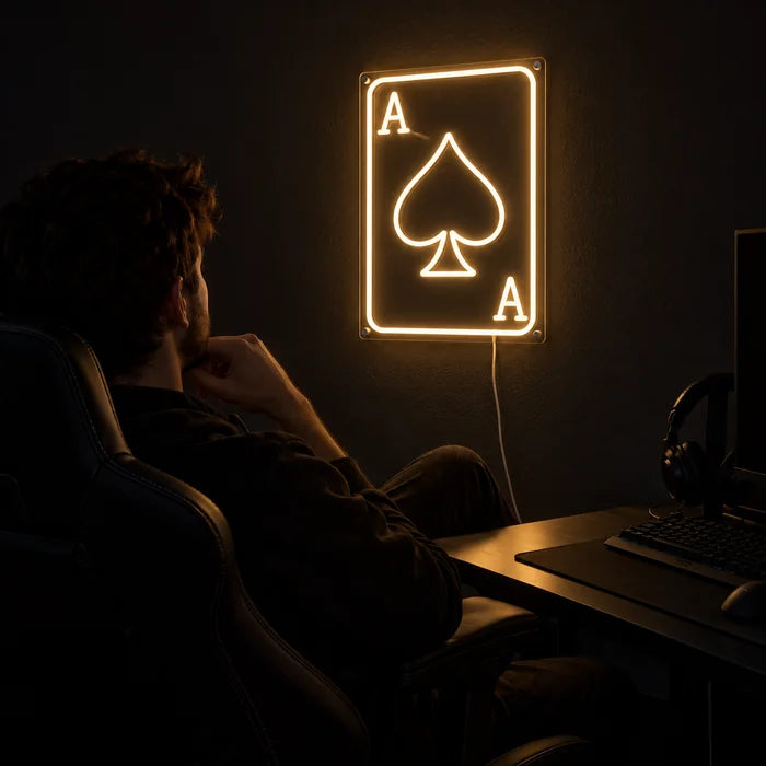 Pik-Ass Neon LED Schild über dem Gaming-Schreibtisch, davor ein Spieler im Gaming-Stuhl