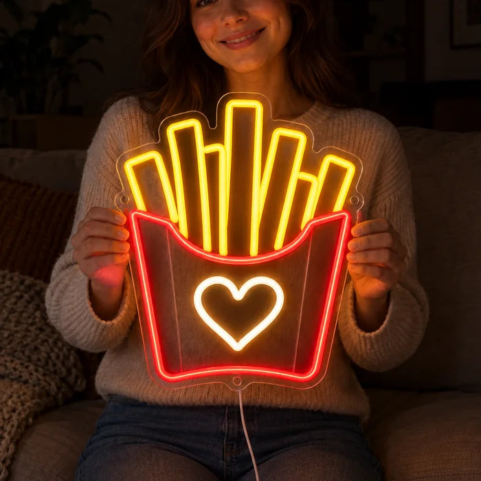 Pommesliebe Neon LED Schild in den Händen einer lächelnden Frau vor dunklem Hintergrund