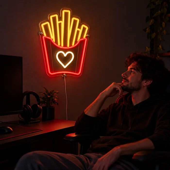 Pommesliebe Neon LED Schild über dem Gaming-Schreibtisch, davor ein Spieler im Gaming-Stuhl