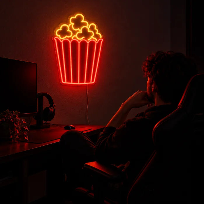 Popcorn Neon LED Schild über dem Gaming-Schreibtisch, davor ein Spieler im Gaming-Stuhl
