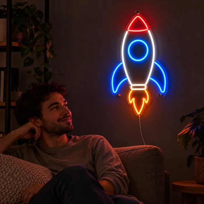 Retro-Rakete Neon LED Schild an der Wohnzimmerwand, davor entspannt eine Person auf dem Sofa