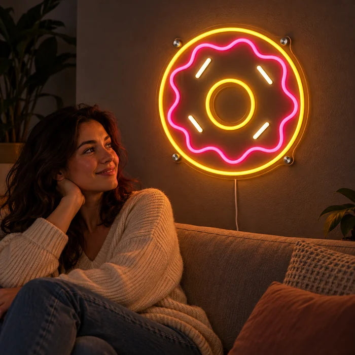 Rosa Donut Neon LED Schild an der Wohnzimmerwand, davor entspannt eine Person auf dem Sofa