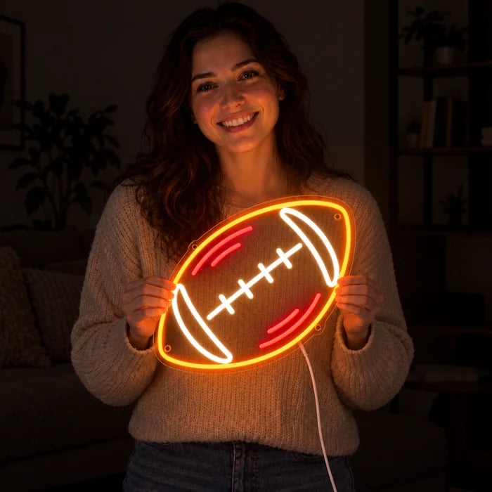 Rugbyball Neon LED Schild in den Händen einer lächelnden Frau vor dunklem Hintergrund