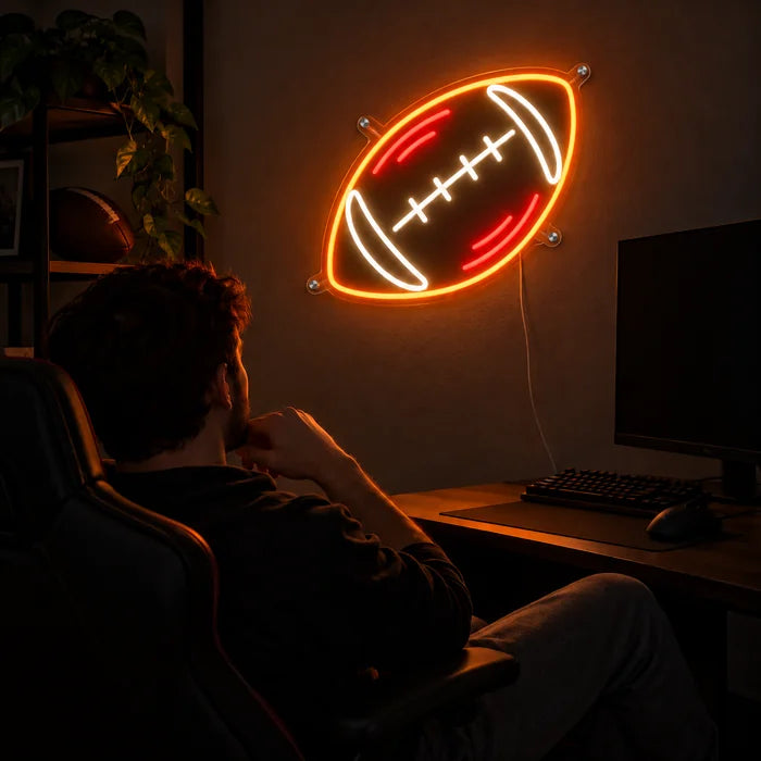 Rugbyball Neon LED Schild über dem Gaming-Schreibtisch, davor ein Spieler im Gaming-Stuhl
