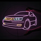 Detailansicht eines Neon-Schildes mit dem Profil eines Saab 9-5. Der Umriss ist violett, die Lichter sind blau und orange hervorgehoben