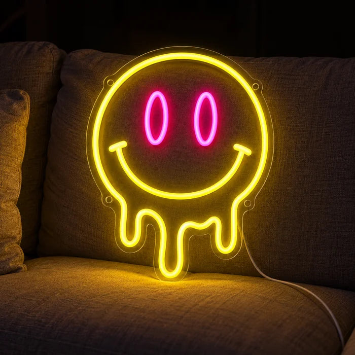 Schmelzender Smiley Neon LED Schild auf einem gemütlichen Sofa zwischen Kissen und Decke