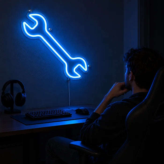 Schraubenschlüssel Neon LED Schild über dem Gaming-Schreibtisch, davor ein Spieler im Gaming-Stuhl