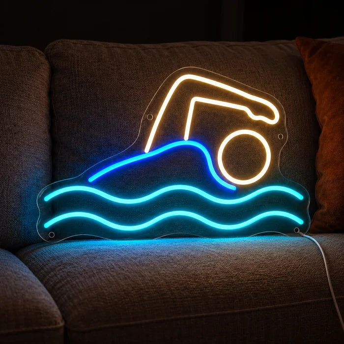 Schwimmer Neon LED Schild auf einem gemütlichen Sofa zwischen Kissen und Decke