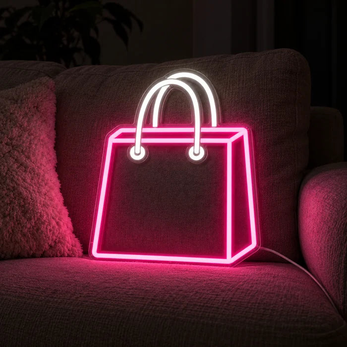 Shoppingtasche Neon LED Schild auf einem gemütlichen Sofa zwischen Kissen und Decke