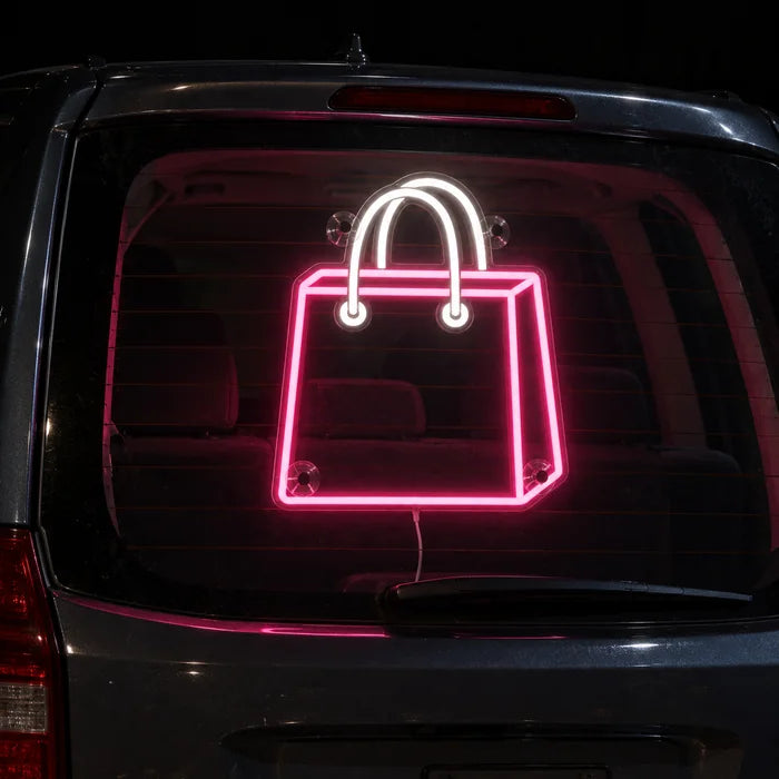 Shoppingtasche Neon LED Schild an der Heckscheibe eines Autos bei Nacht