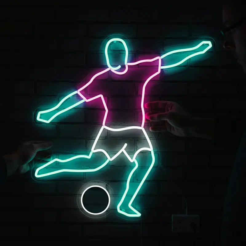 Custom-Neon-Sign eines Fußballers in Aktion mit einem weißen Ball-Umriss, ideal für Sportbars oder Jugendzimmer.
