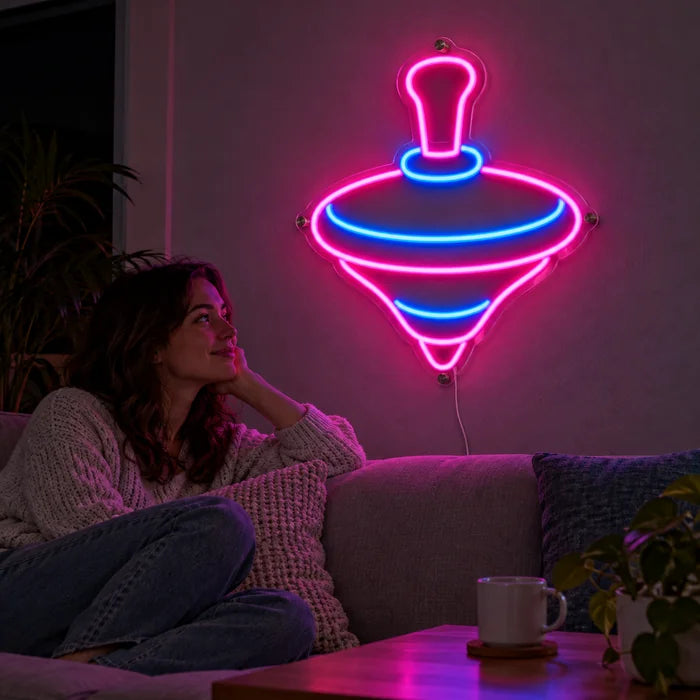 Spielkreisel Neon LED Schild an der Wohnzimmerwand, davor entspannt eine Person auf dem Sofa