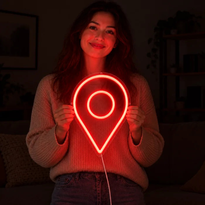 Standortmarker Neon LED Schild in den Händen einer lächelnden Frau vor dunklem Hintergrund