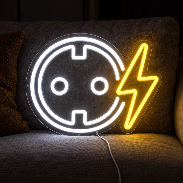 Steckdose mit Blitz Neon LED Schild auf einem gemütlichen Sofa zwischen Kissen und Decke