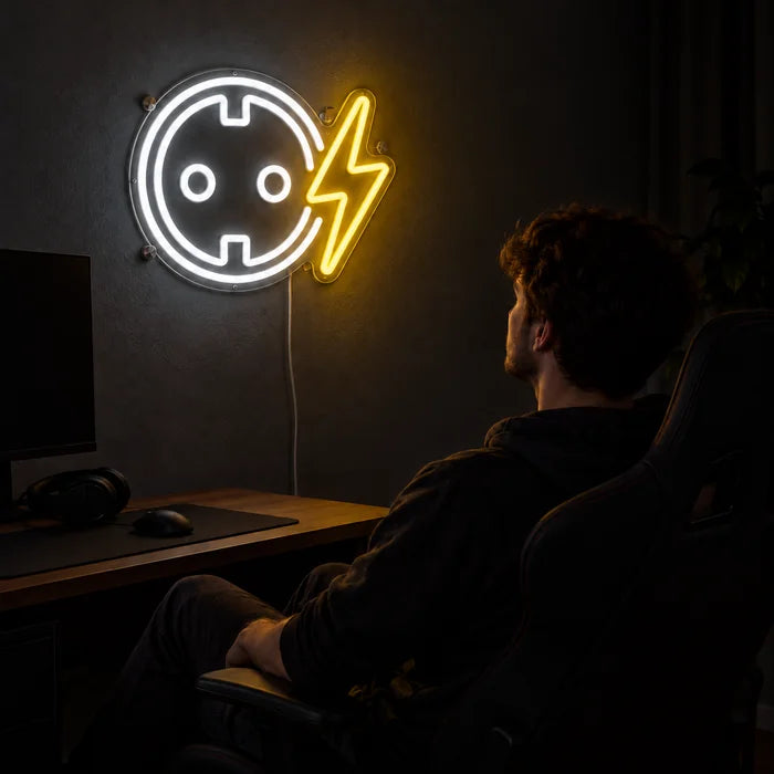 Steckdose mit Blitz Neon LED Schild über dem Gaming-Schreibtisch, davor ein Spieler im Gaming-Stuhl