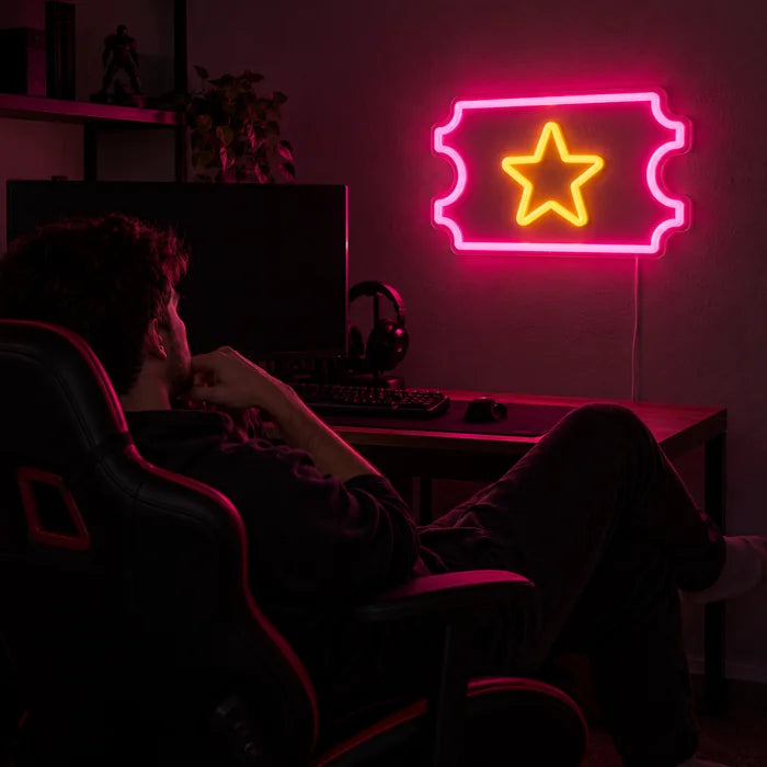 Sternticket Neon LED Schild über dem Gaming-Schreibtisch, davor ein Spieler im Gaming-Stuhl