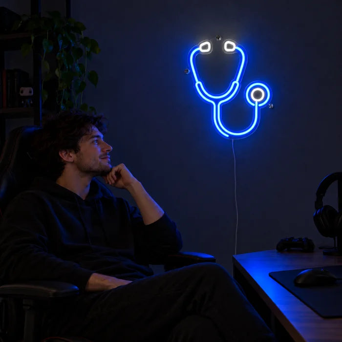 Stethoskop Neon LED Schild über dem Gaming-Schreibtisch, davor ein Spieler im Gaming-Stuhl