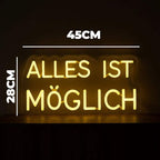 Warm leuchtendes Neon-Zeichen, das den Lebensspruch "ALLES IST MÖGLICH" in zwei Zeilen darstellt und eine Reflexion auf dem Boden erzeugt.